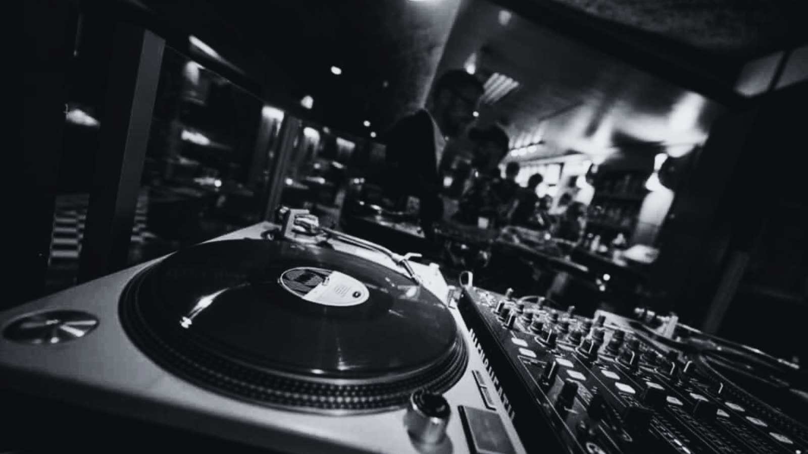 A vinyl record spinning on a turntable in a dim lounge.